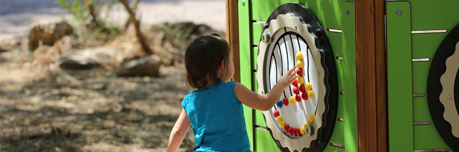 A child interacts with a music play panel at a playground.